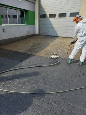 Mężczyzna myjący kostkę brukową z plam po oleju.