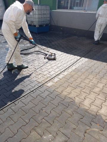 Mężczyzna myjący kostkę brukową z plam po oleju.